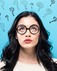 Young woman looking up at all the question marks above her head