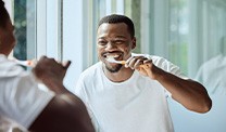 Man smiling while brushing his teeth