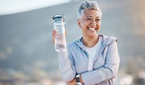 Woman smiling with water bottle on hike outside