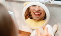Patient with clear aligners smiling at reflection in mirror