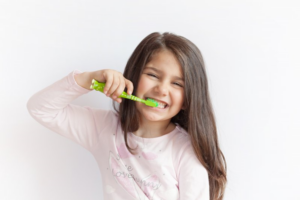 Little girl smiling and brushing her teeth