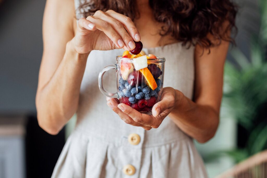 Woman eating cup filled with fruit